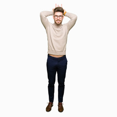 Fototapeta premium Young handsome business man wearing glasses Posing funny and crazy with fingers on head as bunny ears, smiling cheerful