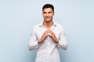 Handsome man over blue wall scheming something