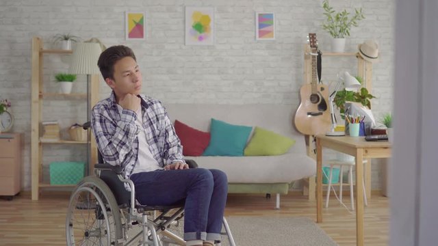 sad young asian man disabled in a wheelchair in the living room