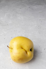 Single ugly yellow apple with dent on  concrete background.