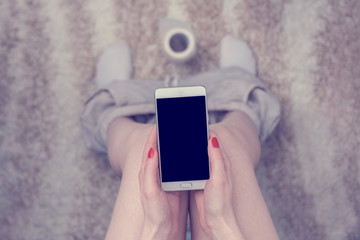 Female legs, girl holds in hands a smartphone, sitting on toilet, top view, copy space, for advertising, slogan, close up