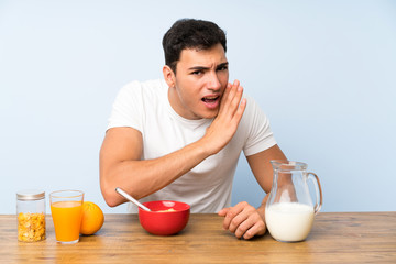 Handsome man in having breakfast whispering something