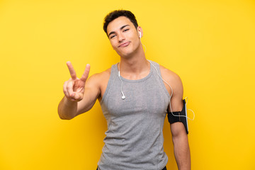 Handsome sport man over isolated background smiling and showing victory sign
