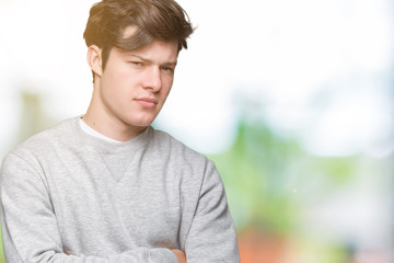 Young handsome sporty man wearing sweatshirt over isolated background skeptic and nervous,...