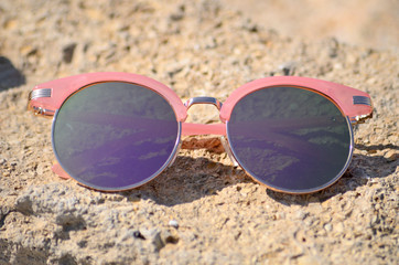 Fototapeta na wymiar Pink sunglasses against the sun on the beach sand