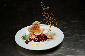 Baked waffles with ice cream. Decorated caramel. Cherry jam and fresh cherry. Beautifully decorated dish for the restaurant on a dark background