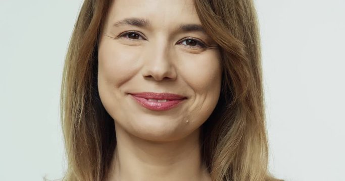 Portrait of the beautiful middle aged Caucasian woman with smooth healthy skin smiling joyfully t the camera. Close up.