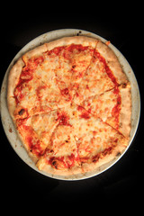 top view of whole four cheese pizza on black background