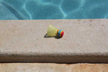 Sonnenhut und Federball liegen am Swimmingpool im Urlaub