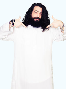 Man wearing Jesus Christ costume looking confident with smile on face, pointing oneself with fingers proud and happy.