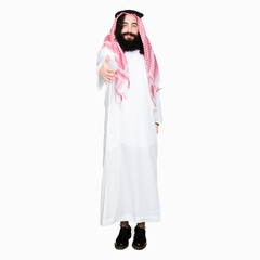 Arabian business man with long hair wearing traditional keffiyeh scarf smiling friendly offering handshake as greeting and welcoming. Successful business.