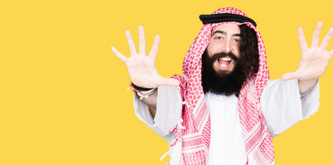 Arabian business man with long hair wearing traditional keffiyeh scarf showing and pointing up with...