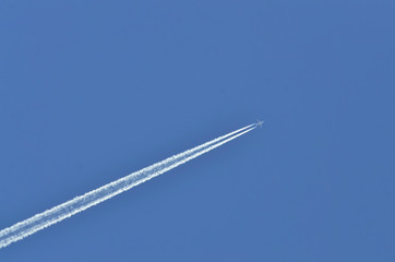 Flugzeug mit Kondensstreifen am blauen Himmel