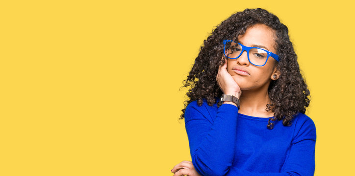 Young beautiful woman with curly hair wearing glasses thinking looking tired and bored with depression problems with crossed arms.
