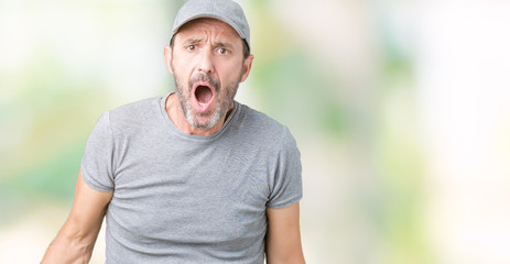 Handsome middle age hoary senior man wearing sport cap over isolated background In shock face, looking skeptical and sarcastic, surprised with open mouth