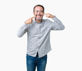 Handsome middle age elegant senior man wearing glasses over isolated background smiling confident showing and pointing with fingers teeth and mouth. Health concept.