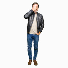 Naklejka premium Middle age handsome man wearing black leather jacket smiling and laughing with hand on face covering eyes for surprise. Blind concept.