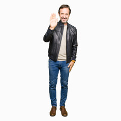 Middle age handsome man wearing black leather jacket Waiving saying hello happy and smiling, friendly welcome gesture