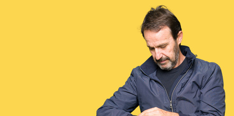 Middle age handsome man wearing a jacket Checking the time on wrist watch, relaxed and confident