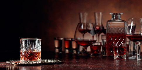 Set of strong alcoholic beverages in glasses on a brown background.
