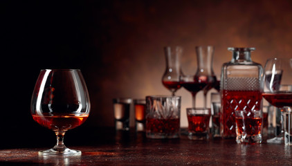Set of strong alcoholic beverages in glasses on a brown background.