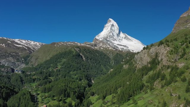 Aerial view of Matterhorn mountain at turn of spring and summer, picturesque scenery of Swiss Alps Mountains, snowy peaks and lush green valley - landscape panorama of Switzerland from above, Europe