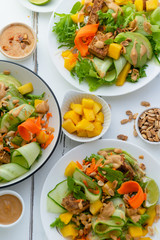 Healthy summer fresh salad with mango, avocado, lime and tofu with sweet peanut butter dressing on white wooden table