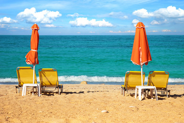 Abstract image with sun loungers and orange umbrellas from the sun on the beach on the seafront with waves (relaxation, harmony, holidays - concept)