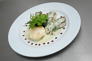 Fried fish with parsley and corn in white sauce on a gray background. Close-up.