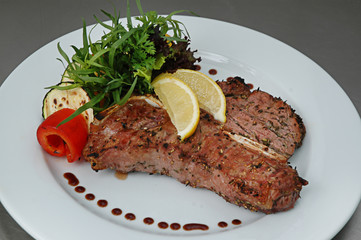 Steak beef with lemon, fried zucchini and pepper. Isolated on gray background