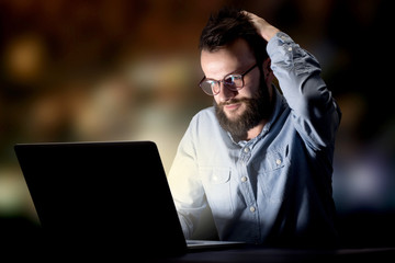 Young handsome businessman working late at night in the office