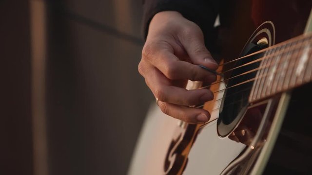 Men playing guitar on the beach at sunset, close up. Slow motion