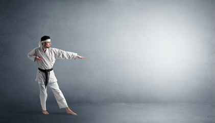 Small karate man fighting in an empty grey copy space