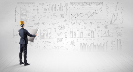 Engineer with construction helmet holding a plan and standing with graphs, charts and reports on the background