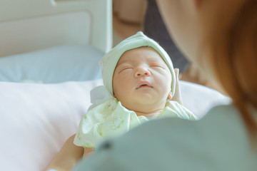 Fototapeta na wymiar Newborn baby boy sleeping in asian mother hand at hospital