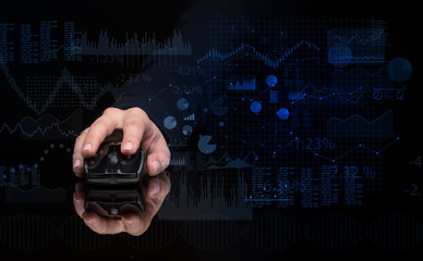Hand using wireless mouse with financial concept on dark background
