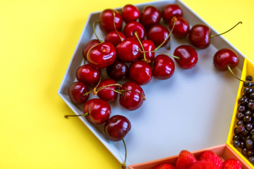 Cherries, strawberries, blue berries on yellow background. Colorful concept. Natural organic vegan healthy fresh food.