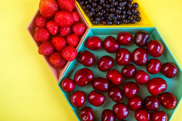 Cherries, strawberries, blue berries on yellow background. Colorful concept. Natural organic vegan healthy fresh food.