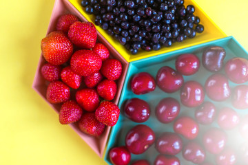 Cherries, strawberries, blue berries on yellow background. Colorful concept. Natural organic vegan healthy fresh food.