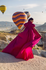 sexy young girl in a long purple dress stands on a mountain against
