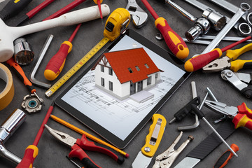 Fototapeta premium Tablet with construction tools and 3d home plan concept 