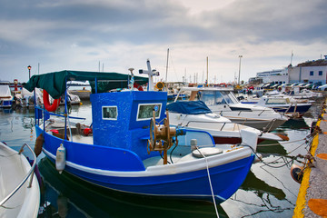 Fototapeta premium Greek fishing boats stays parked near sea pier at Vlychada town on Santorini island