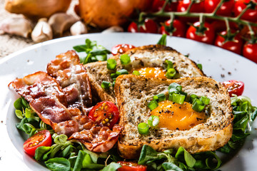 Breakfast - toasted bread with fried egg, bacon and vegetables