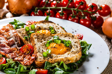Breakfast - toasted bread with fried egg, bacon and vegetables