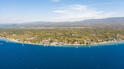 Fototapeta premium Coast of Cebu island, Moalboal, Philippines, top view. Philippine boats in a blue lagoon over coral reefs. Moalboal is a great place for diving and vacations.