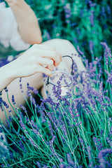 A beautiful female hand holding a transparent candle holder on the lavender field