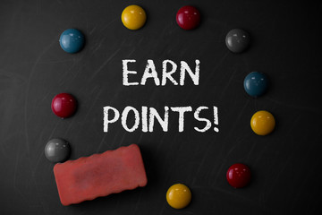 Word writing text Earn Points. Business photo showcasing collecting big scores in order qualify to win big prize Round Flat shape stones with one eraser stick to old chalk black board