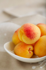 Ripe apricots on a white plate on a light background