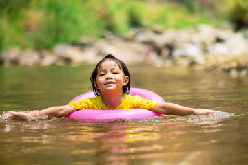 Fototapeta premium Little girl in pink pool ring swimming in water