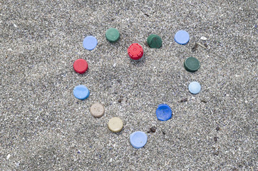 Heart of old plastic bottle caps on beach